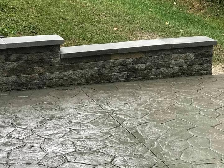 Sealed flagstone-pattern patio with stone wall cap close-up