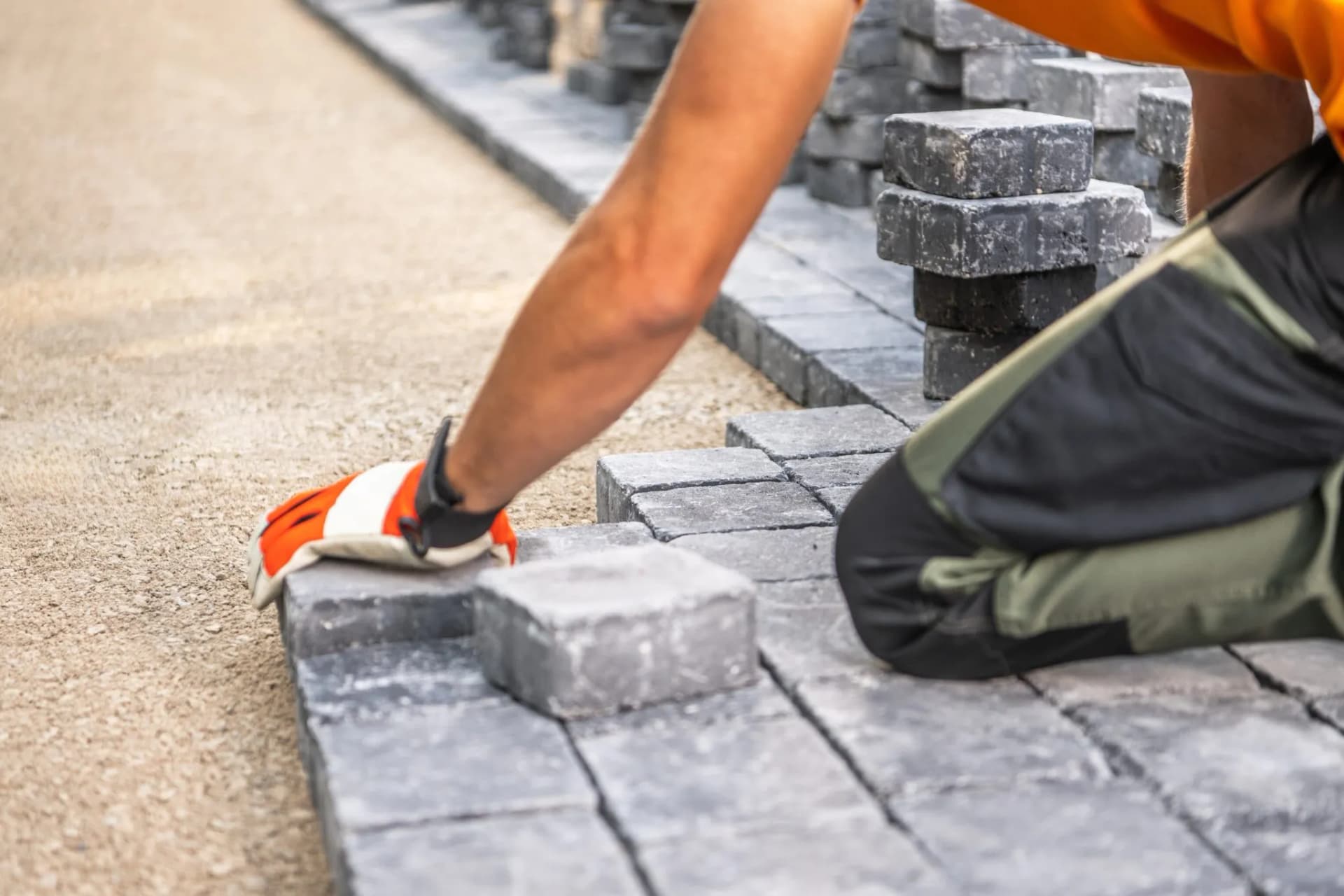 Crew hand-setting interlocking pavers on a prepared stone base