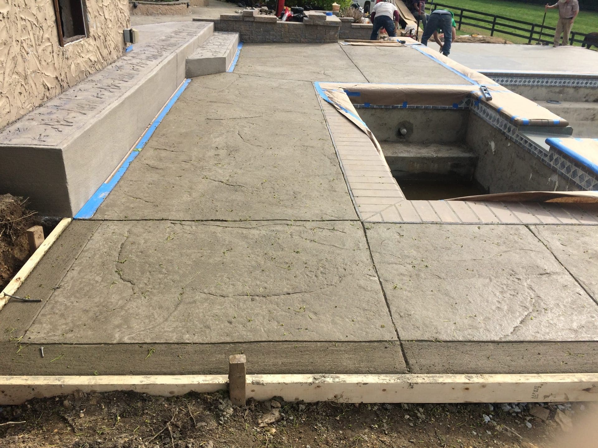 Stamped concrete pool deck being poured and textured around an in-ground pool