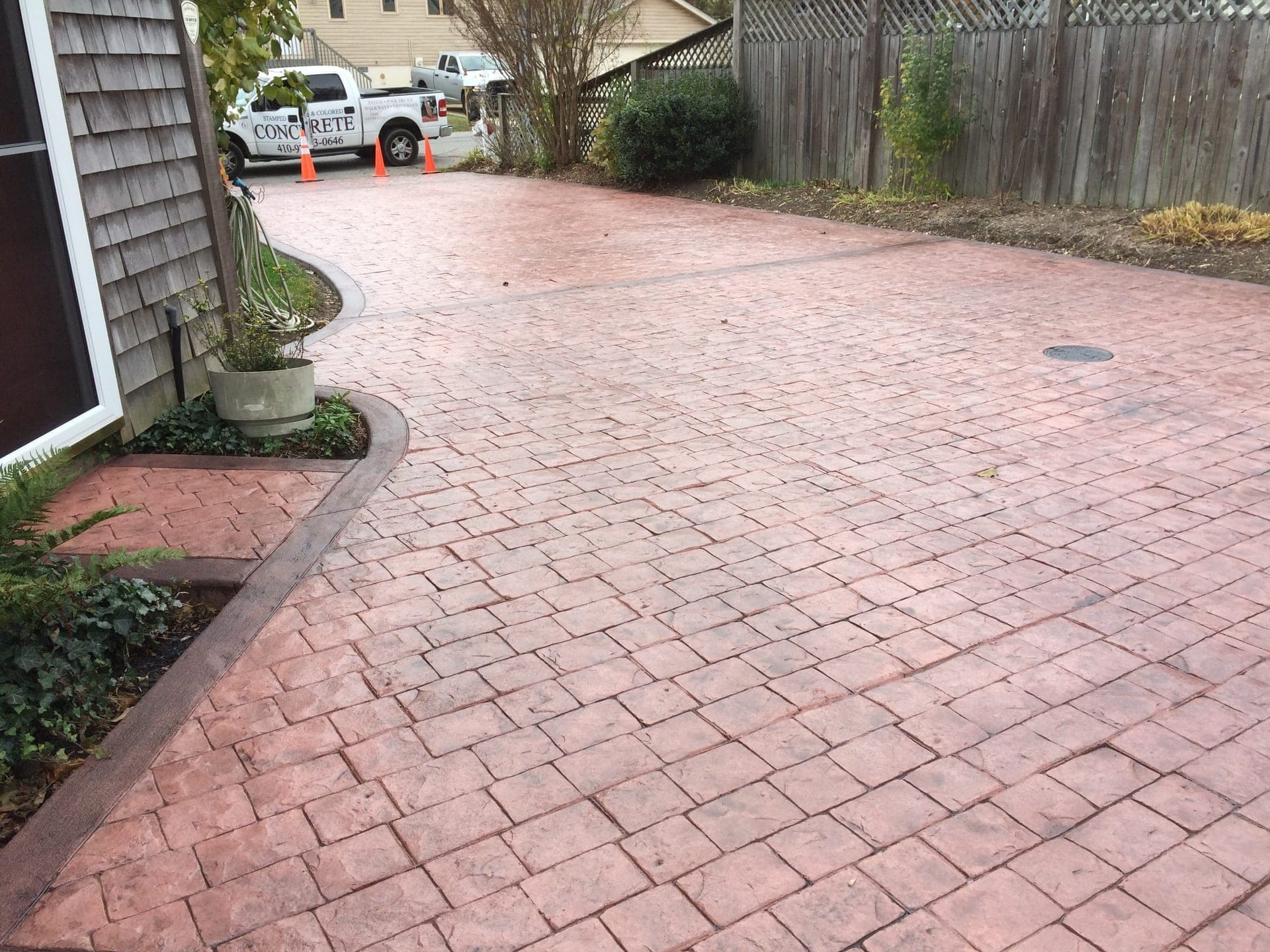 Cobblestone-pattern concrete patio and drive with contrasting border in warm red tones